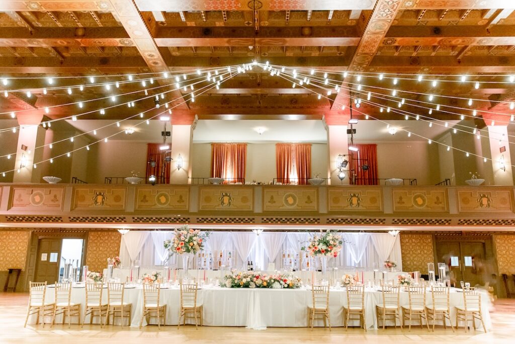 Elegant wedding reception venue with decorated tables, floral centerpieces, and string lights creating a romantic ambiance.