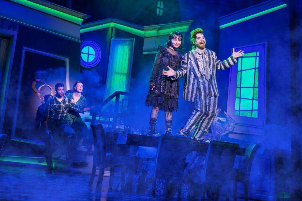 Actors performing on vibrant stage with dramatic lighting and costumes, creating a mysterious and immersive theater scene.