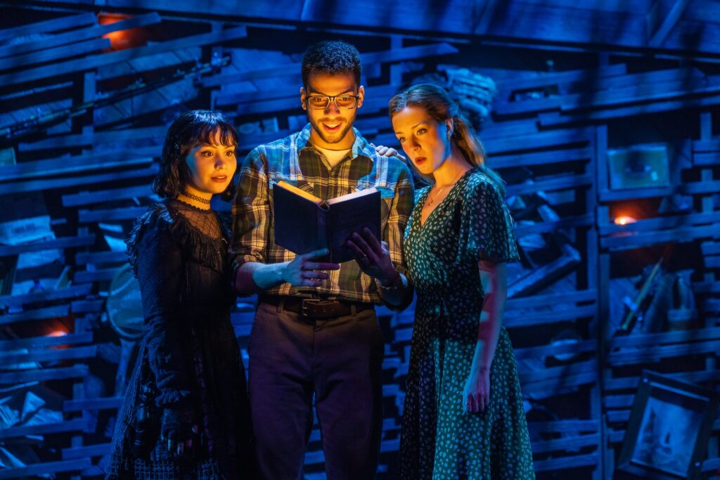 Actors reading a mysterious book on stage with dramatic lighting and expressive emotions.